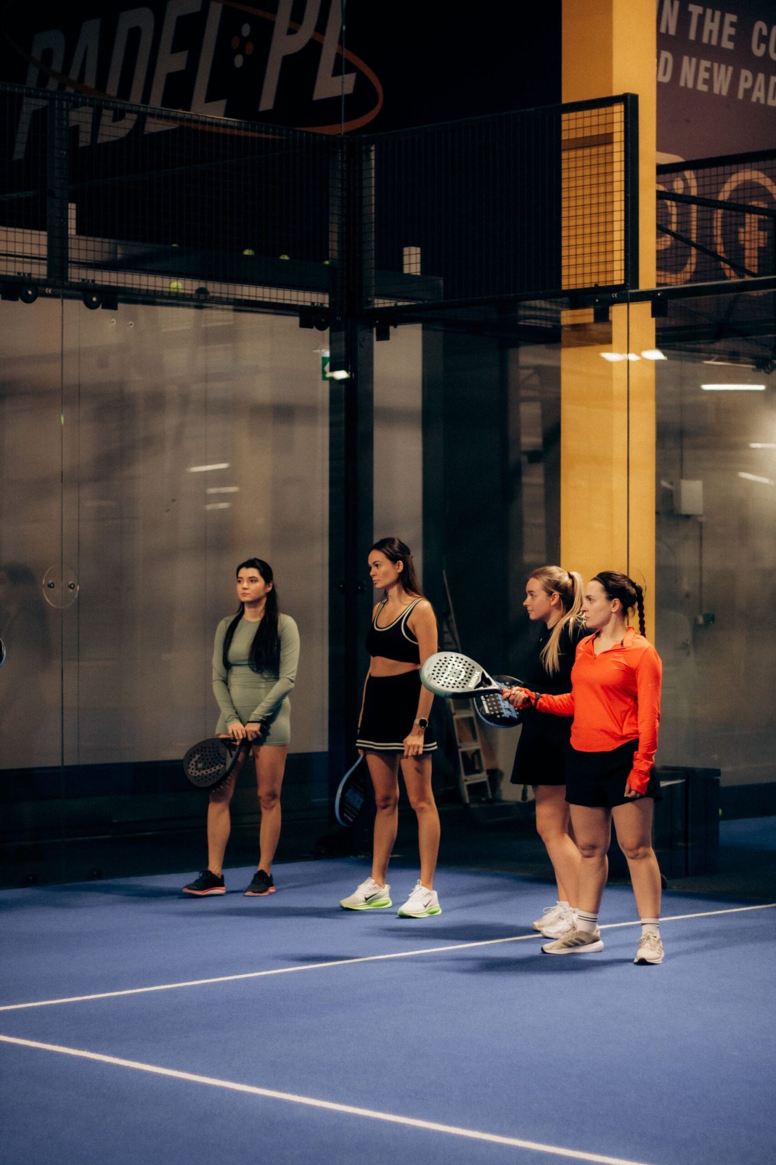 Quatre joueuses avec raquettes sur terrain de padel